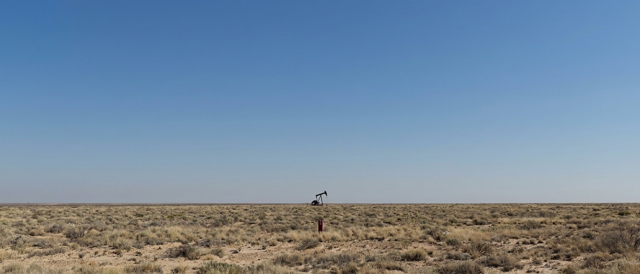 A lone pumpjack on the open Permian Basin plain under a clear West Texas sky.